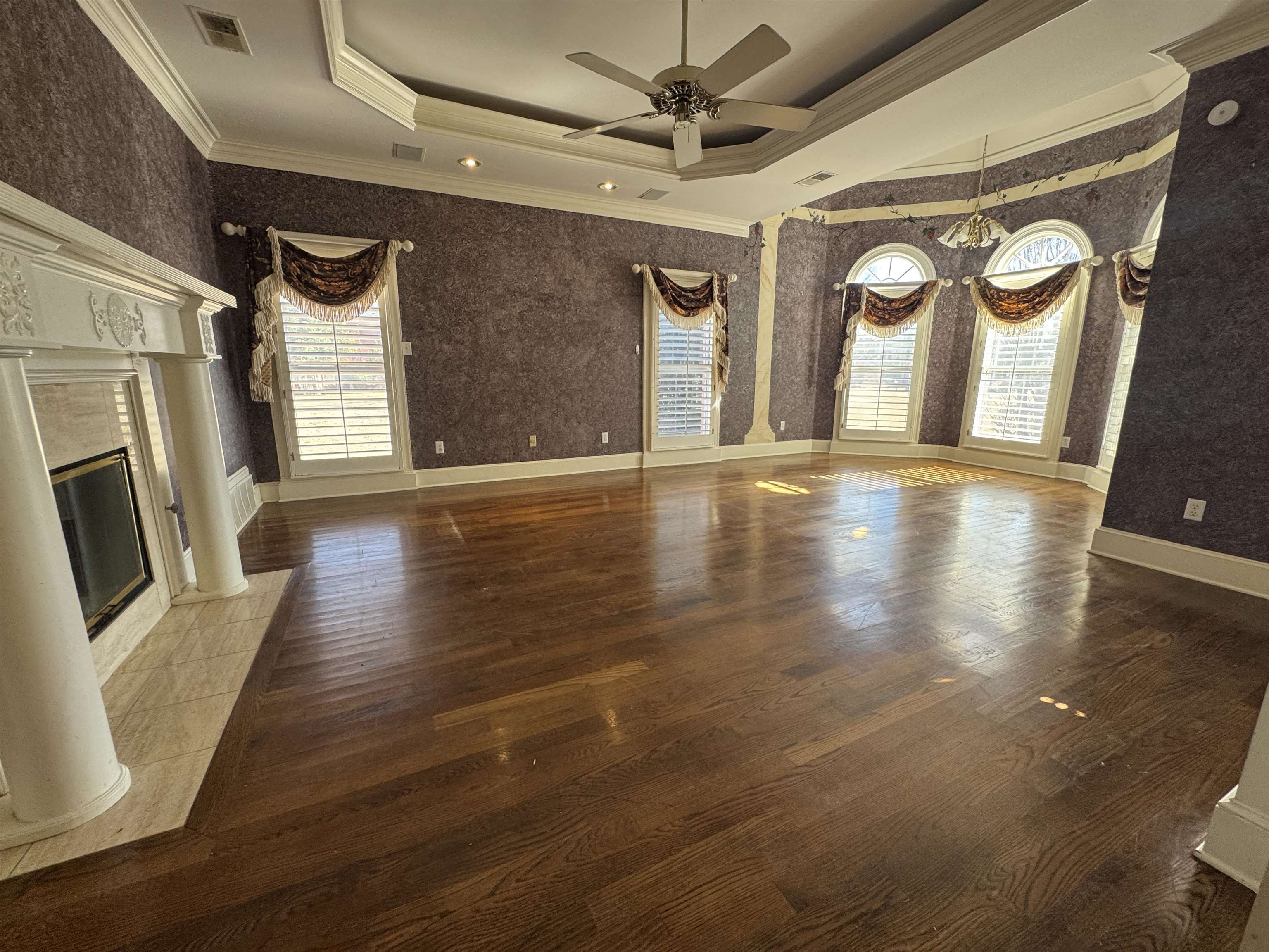 9500 Plantation Lake Road Collierville, TN 38017 - Photo 6 of 40 Unfurnished living room with wallpapered walls, visible vents, a raised ceiling, ceiling fan with notable chandelier, and wood finished floors