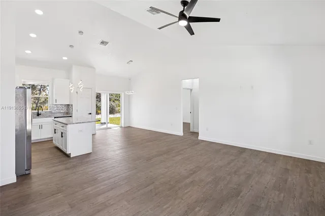 a view of open kitchen with stove and white cabinets