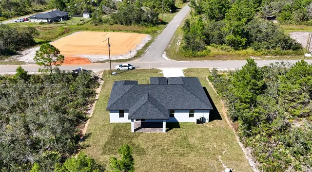 an aerial view of a house with swimming pool and large trees