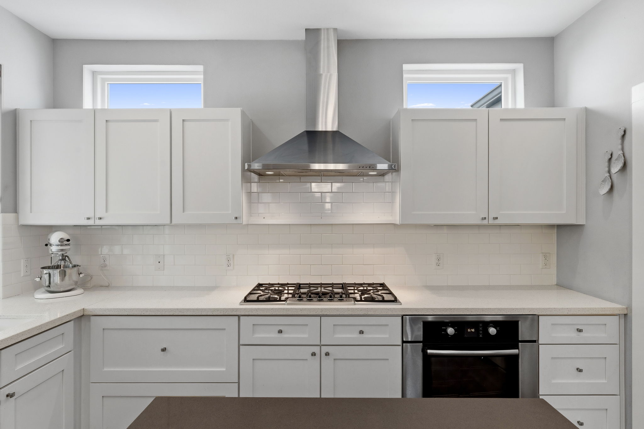 1303 Azie Morton Road, Unit 2 Austin, TX 78704 - Photo 10 of 37 Bright kitchen with white cabinetry, sleek quartz countertops, and stainless steel appliances including a vent hood and gas cooktop.