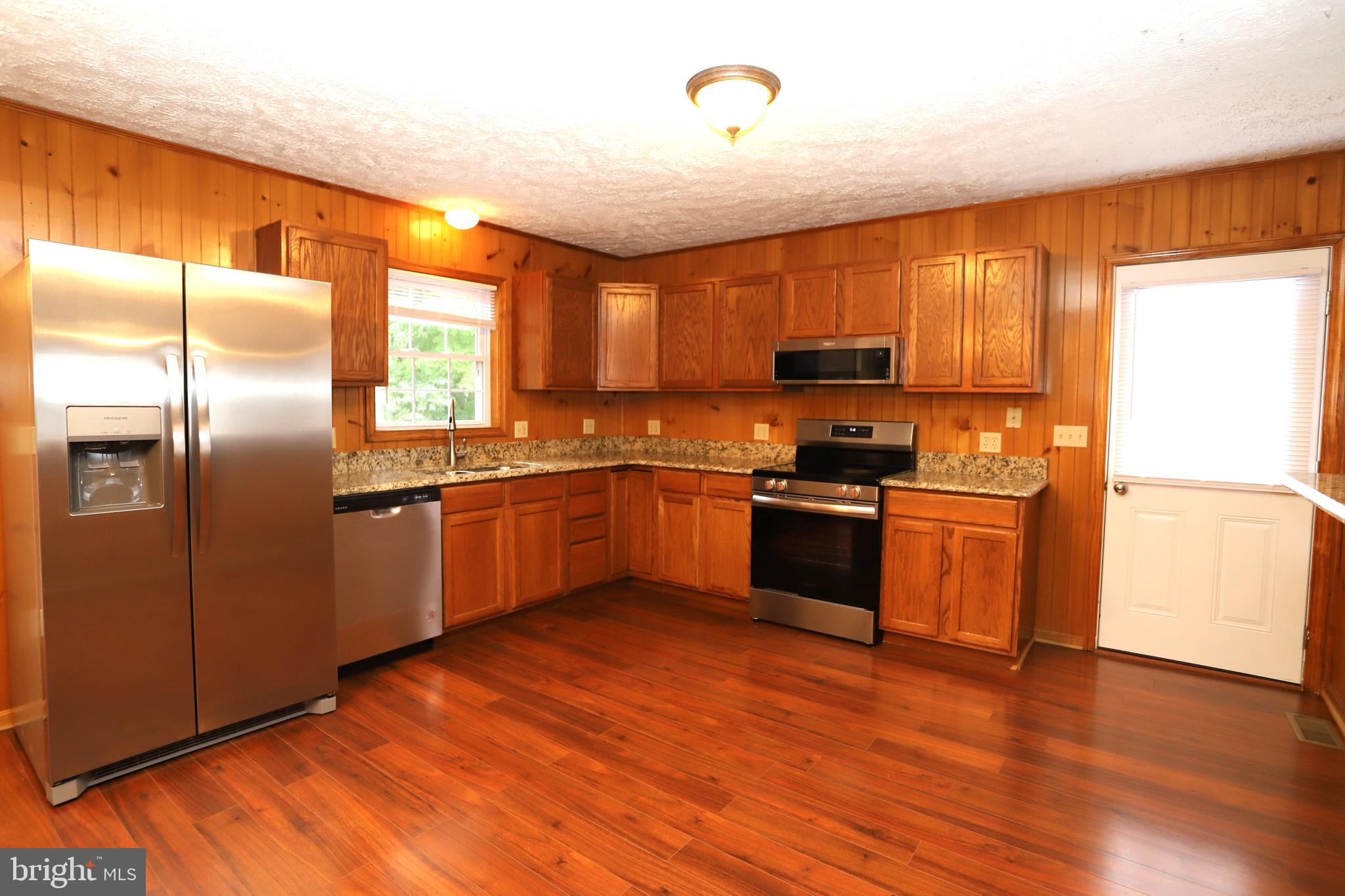 14459 Norman Road Culpeper, VA 22701 - Photo 8 of 23 a kitchen with granite countertop a refrigerator and wooden floors