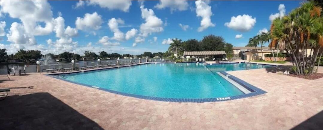 100 Ashbury Road, Unit 206 Hollywood, FL 33024 - Photo 23 of 23 a view of a swimming pool with a table and chairs under an umbrella