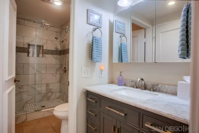 a bathroom with a granite countertop sink a toilet a mirror and shower