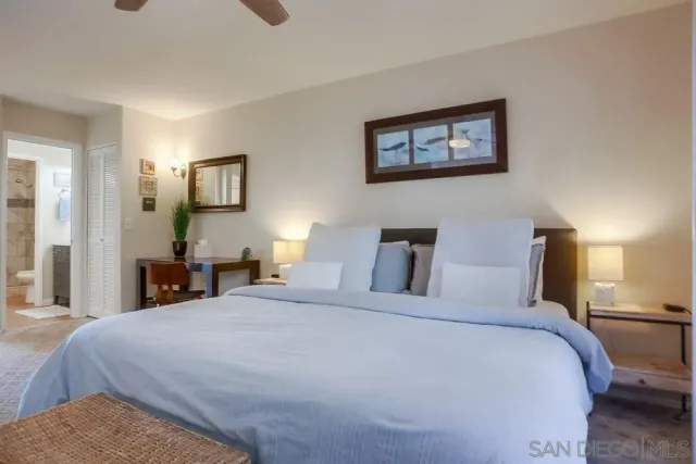 a bedroom with a bed a painting on the wall and a lamp