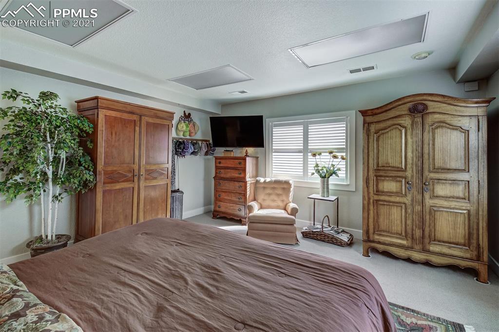 8977 Spruce Mountain Road Larkspur, CO 80118 - Photo 34 of 50 a bedroom with a bed closet and flat tv screen