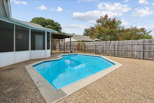 a view of a backyard with a swimming pool and wooden fence