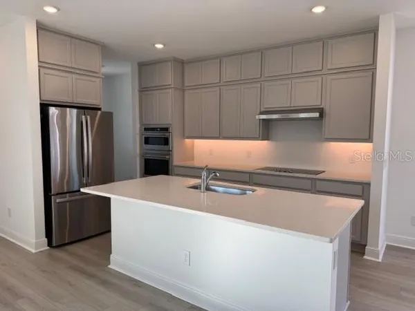 a kitchen with kitchen island a refrigerator and a stove top oven