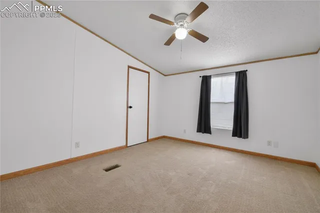 an empty room with chandelier fan and windows