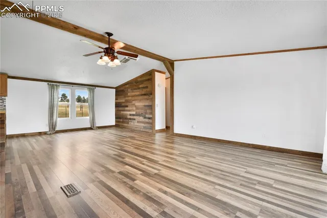 a view of an empty room with a window and wooden floor