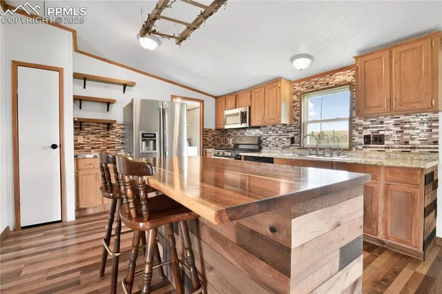 a kitchen with stainless steel appliances granite countertop wooden cabinets a dining table and chairs