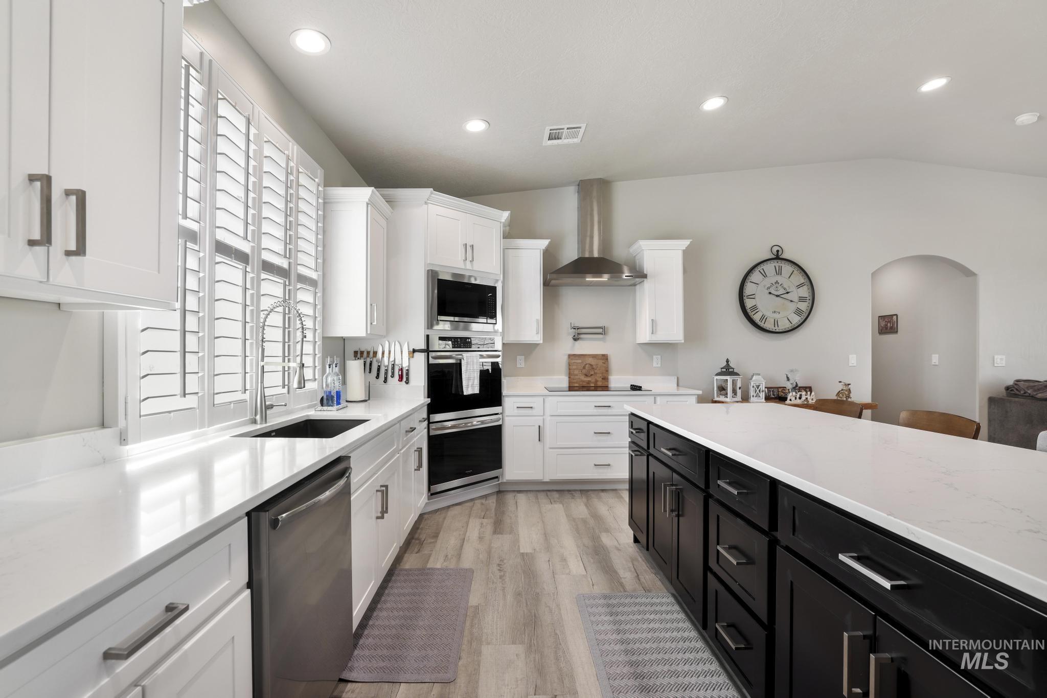 758 Cedar Crk Road Rogerson, ID 83302 - Photo 7 of 50 Kitchen featuring a large island with dark cabinetry and light-toned countertops, white perimeter cabinetry, stainless steel appliances, and wood-finish flooring