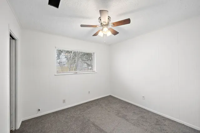 an empty room with a window and a fan