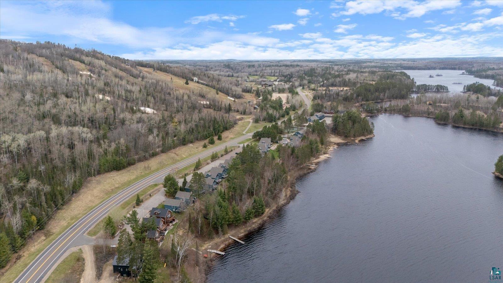 6266 Giants Ridge Road Biwabik, MN 55705 - Photo 18 of 37 Lakeside properties with private docks situated along a paved road, bordered by a forested hillside