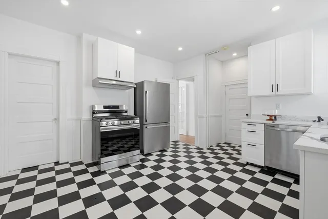 a kitchen with a checkered floor and white cabinets