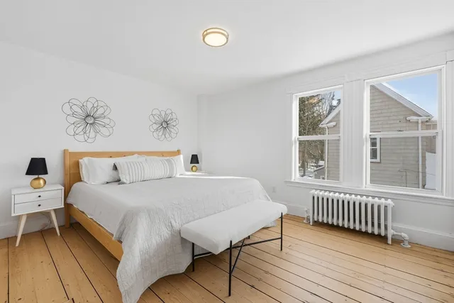 a bedroom with a bed and a window with wooden floor