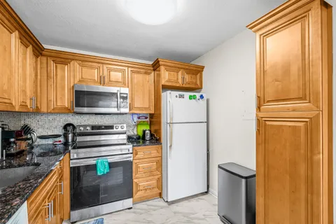 a kitchen with a refrigerator a stove top oven and a window
