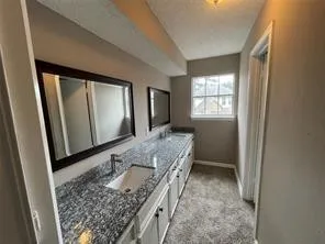 a en suite bathroom with a granite countertop sink and a mirror
