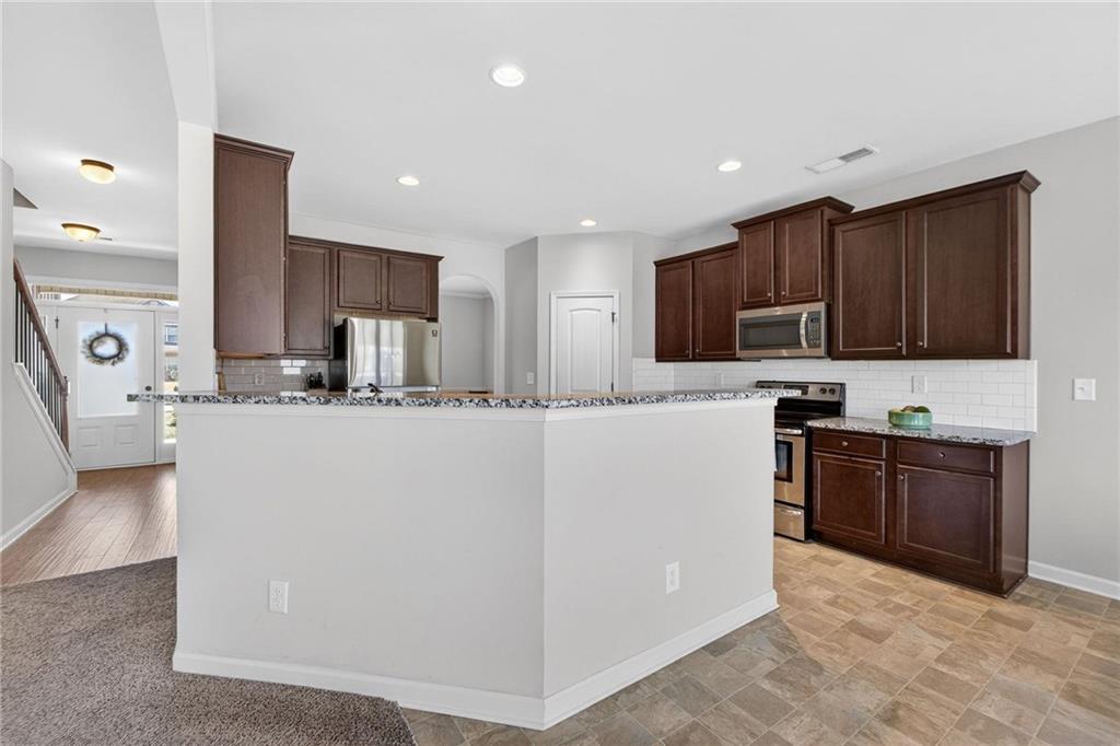 214 Millie Court Jackson, GA 30233 - Photo 17 of 61 a kitchen with kitchen island granite countertop wooden cabinets and white appliances