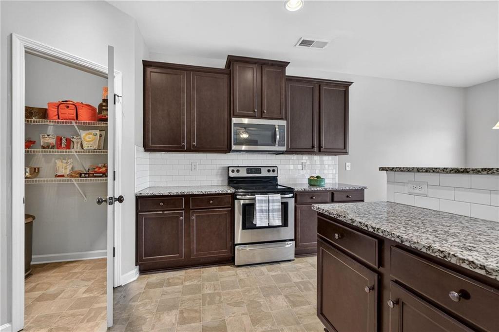 214 Millie Court Jackson, GA 30233 - Photo 21 of 61 a kitchen with granite countertop wooden cabinets and stainless steel appliances