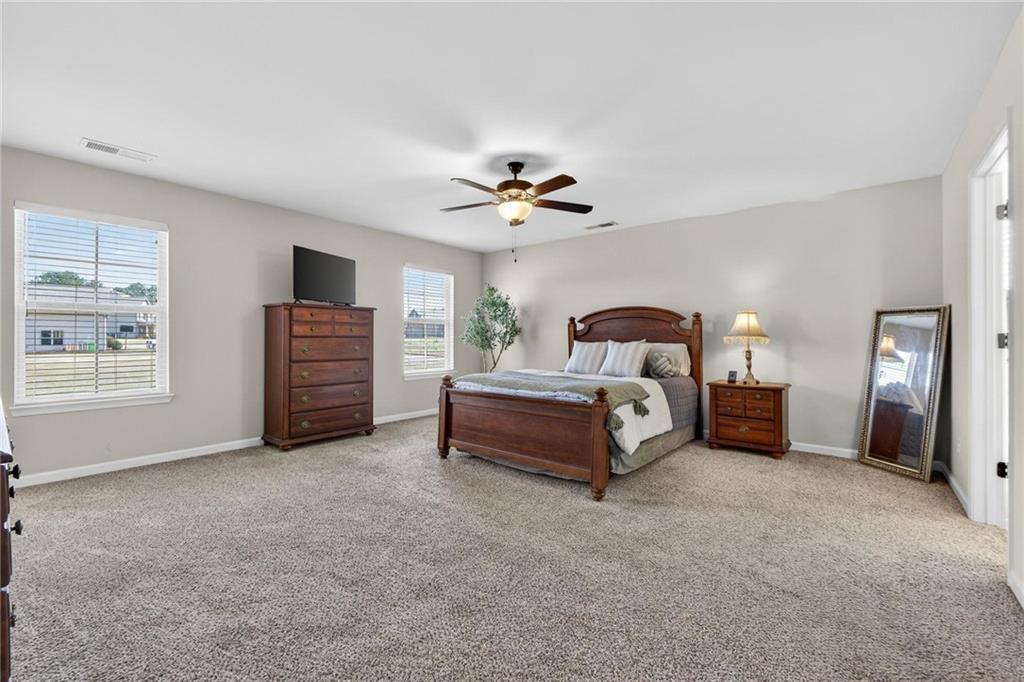 214 Millie Court Jackson, GA 30233 - Photo 31 of 61 a spacious bedroom with a bed and a ceiling fan