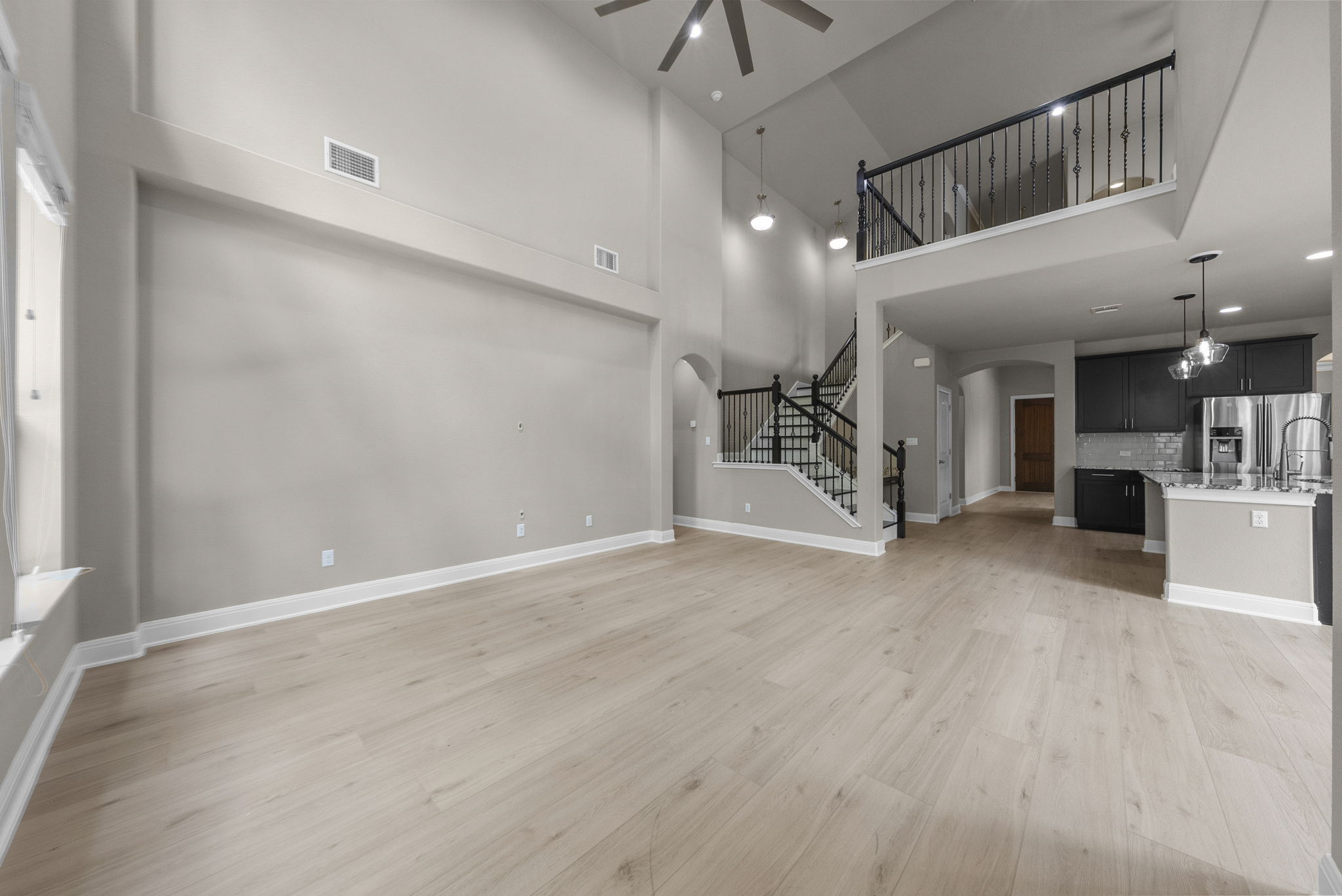 4401 Trinity Woods Street Leander, TX 78641 - Photo 4 of 37 A grand living area boasts soaring ceilings and light wood flooring, seamlessly connecting to an elegant kitchen.