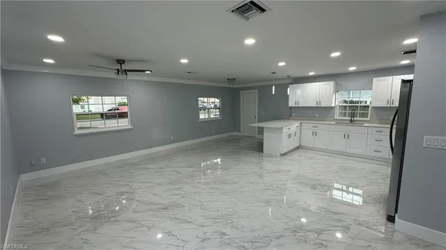 a open kitchen with stainless steel appliances granite countertop a refrigerator a sink a stove and a refrigerator with wooden floor