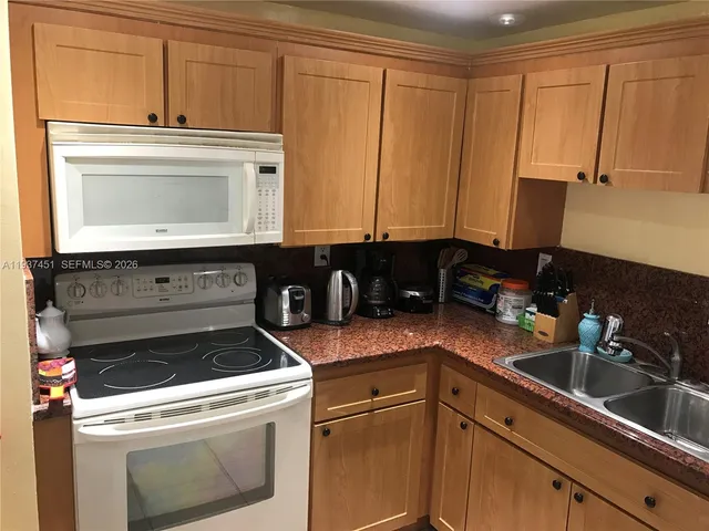a kitchen with granite countertop white cabinets and black appliances