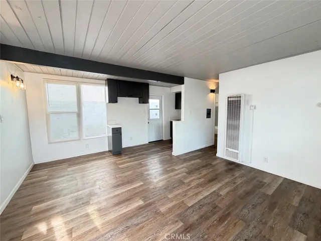 a view of empty room with wooden floor and white walls