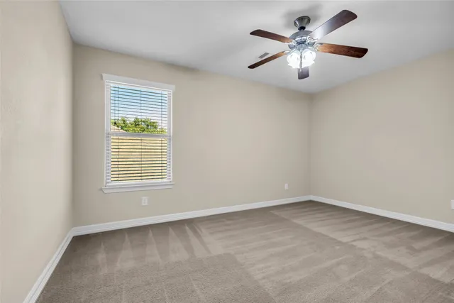 an empty room with a chandelier fan and windows