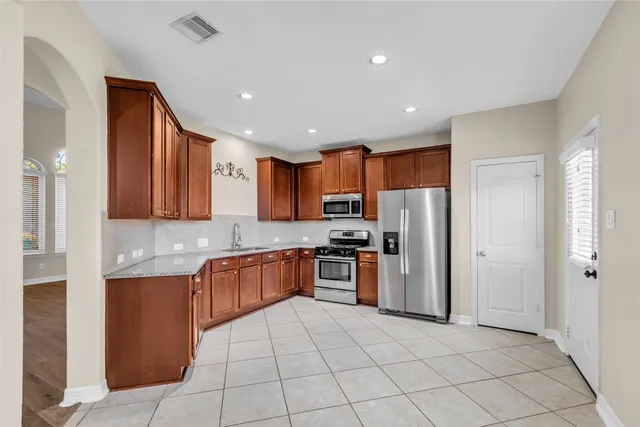 a kitchen with stainless steel appliances granite countertop a refrigerator and a stove top oven