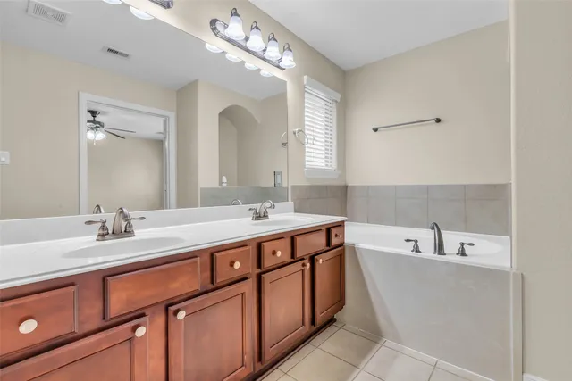 a spacious bathroom with a tub double sink and mirror