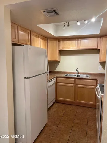 a view of a dining room with a chandelier fan and a refrigerator