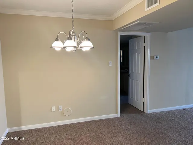 an empty room with a chandelier fan and windows