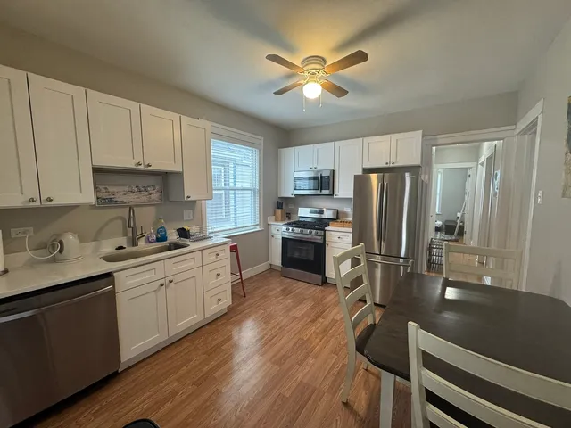a kitchen with a refrigerator a sink cabinets and wooden floor