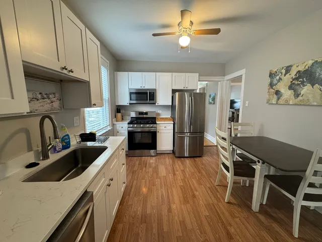 a kitchen with kitchen island granite countertop a sink appliances cabinets and furniture