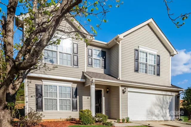 a view of a white house with large windows and a tree