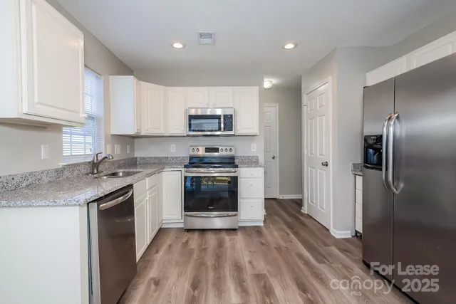 a kitchen with stainless steel appliances granite countertop a refrigerator a stove a sink and a microwave