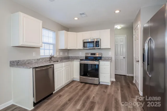a kitchen with kitchen island granite countertop a sink cabinets and stainless steel appliances