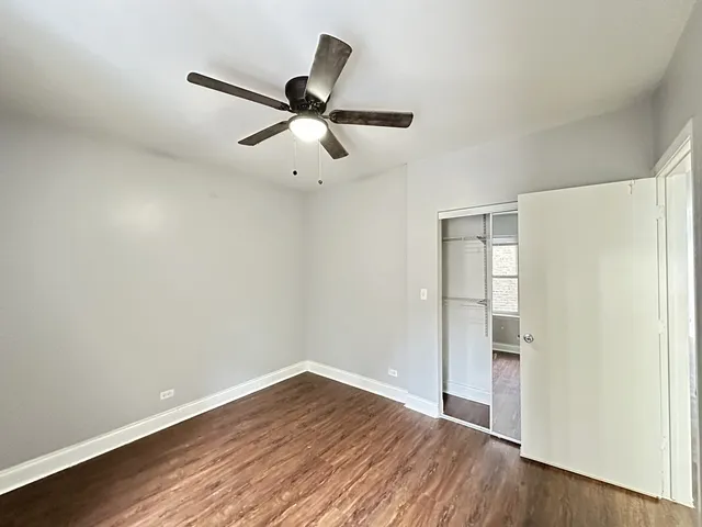 an empty room with wooden floor closet and ceiling fan