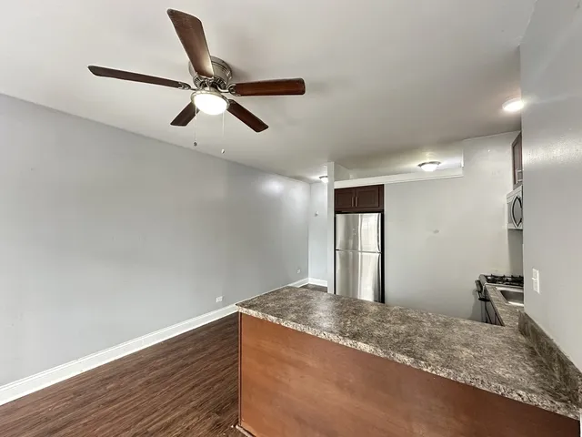 a view of a room with a ceiling fan and wooden floor