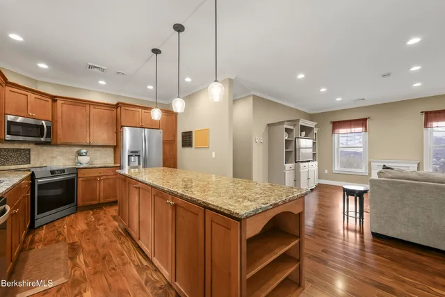 a kitchen with stainless steel appliances granite countertop a kitchen island a stove and a sink