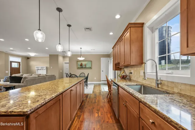 a large kitchen with granite countertop a large counter top a sink stainless steel appliances and cabinets