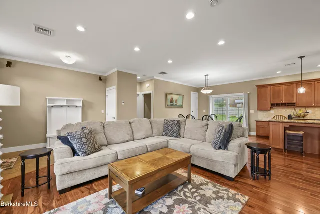 a living room with furniture kitchen view and a wooden floor