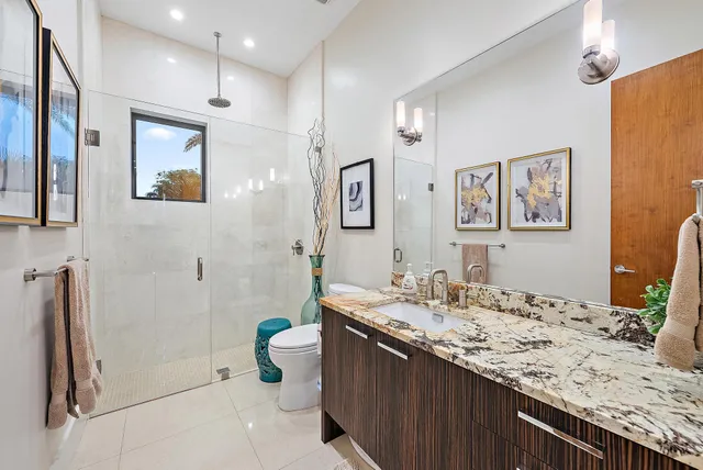 a bathroom with a granite countertop sink a toilet a shower and a mirror