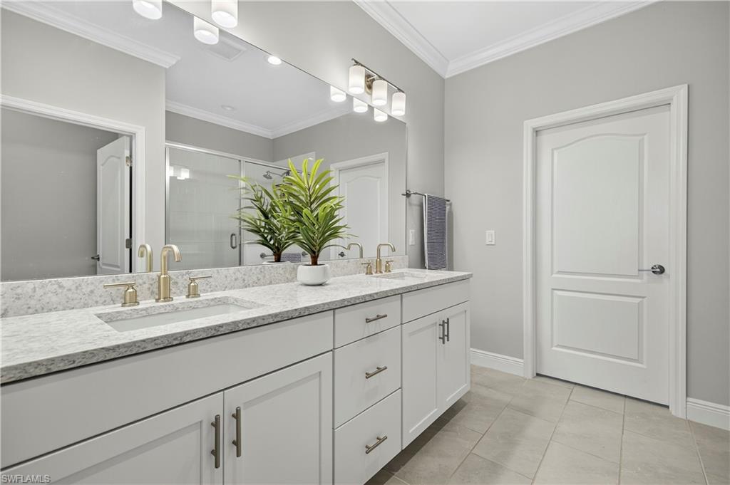 2319 Sawyers Hill Road, Unit 705 Naples, FL 34102 - Photo 16 of 29 Full bath with double vanity, a shower stall, light tile patterned flooring, and ornamental molding