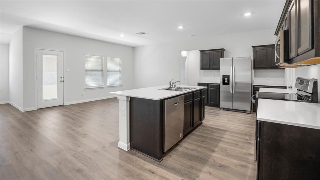 1921 Reveille Way Terrell, TX 75160 - Photo 13 of 30 a kitchen with stainless steel appliances granite countertop a sink a stove top oven a refrigerator with wooden floors