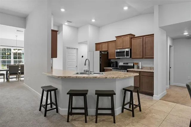 a kitchen with stainless steel appliances granite countertop a stove a sink a microwave a refrigerator and chairs