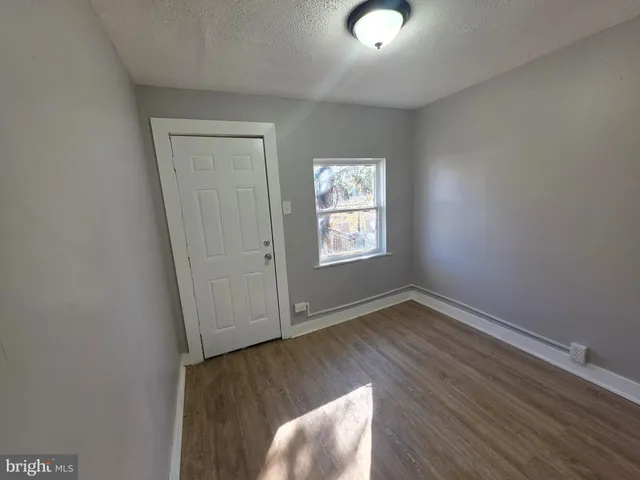 an empty room with wooden floor cabinet and windows