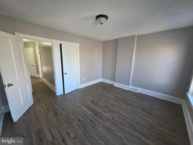 an empty room with wooden floor and entrance