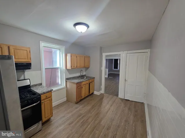 a large kitchen with a wooden floor and stainless steel appliances